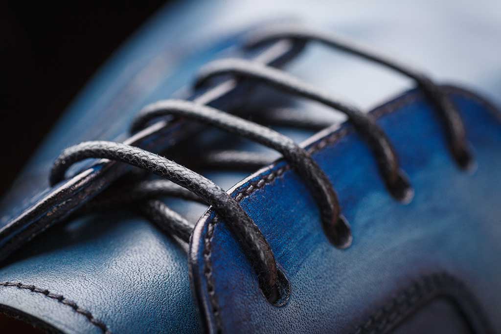 What benefits do waxed laces bring in terms of resistance to water and wear?